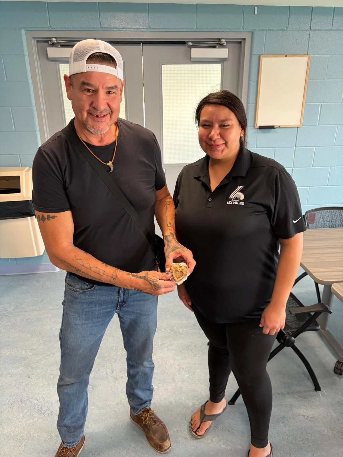 Two people together in an office, one holding a heart-shaped object
